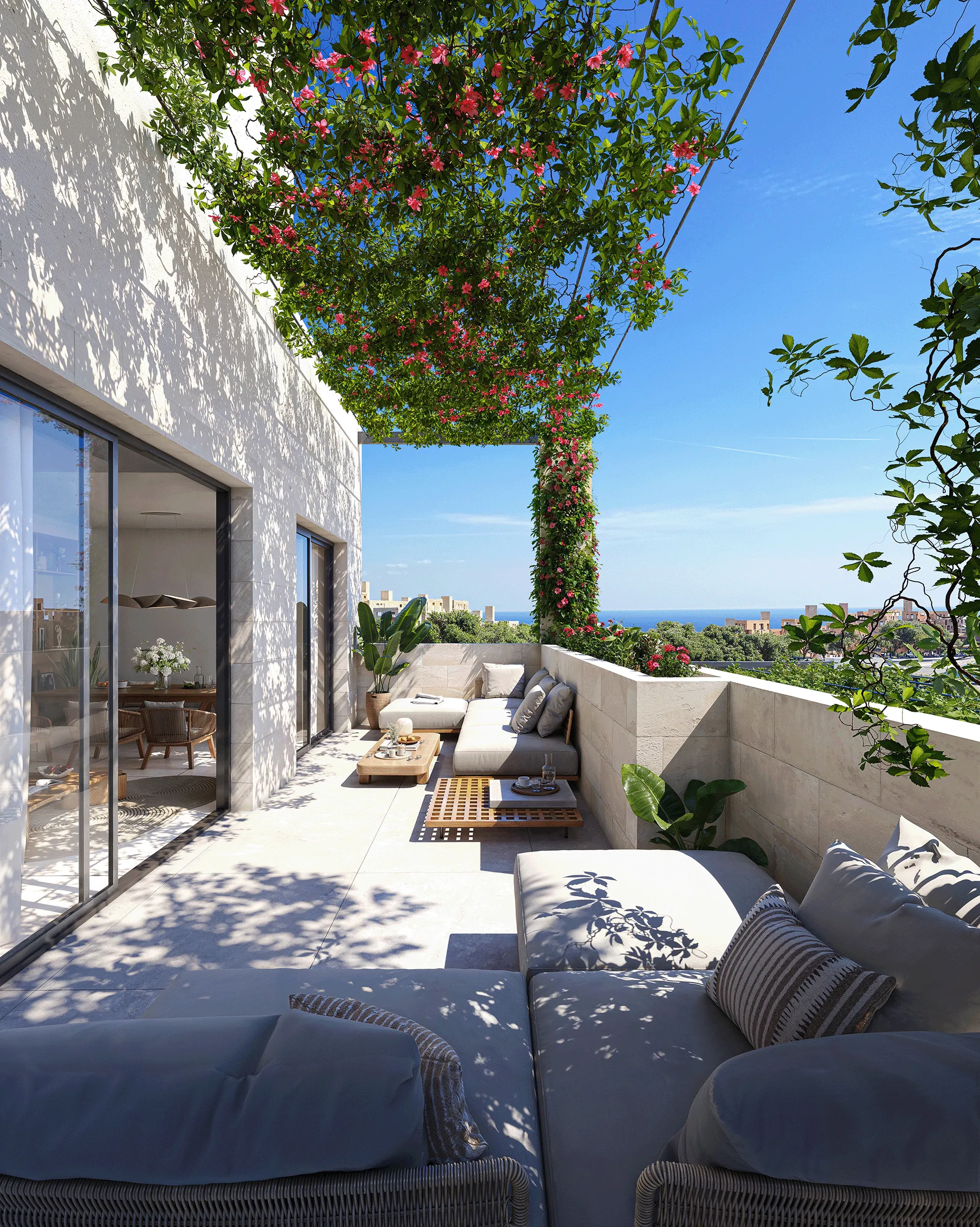 Sunlit modern terrace with cushioned sofas, wooden tables, climbing plants, and ocean view under clear sky.